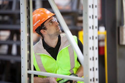 A pallet rack engineer inspecting warehouse racks